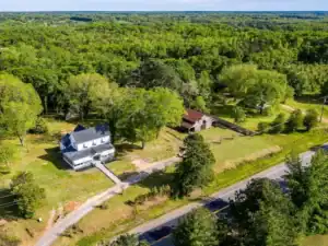 Aerial view of white farmhouse and barn in rural countryside